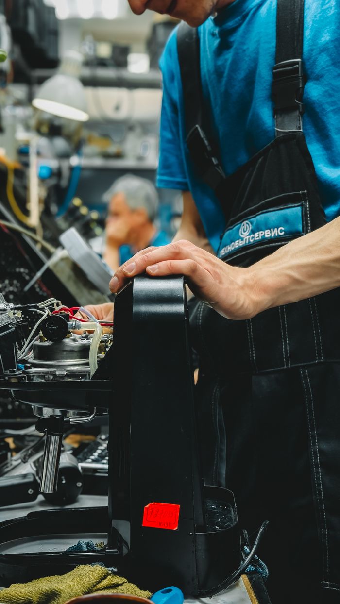 about-01 Technician repairing a coffee machine in an industrial workshop with precision.