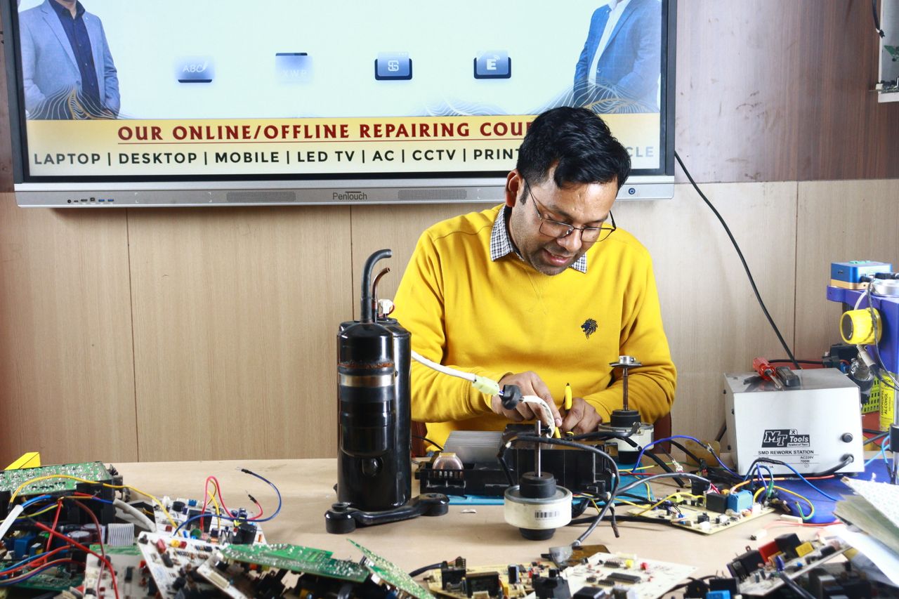 hero-01 Technician engaged in AC repair at a New Delhi workshop. Indoor learning session.