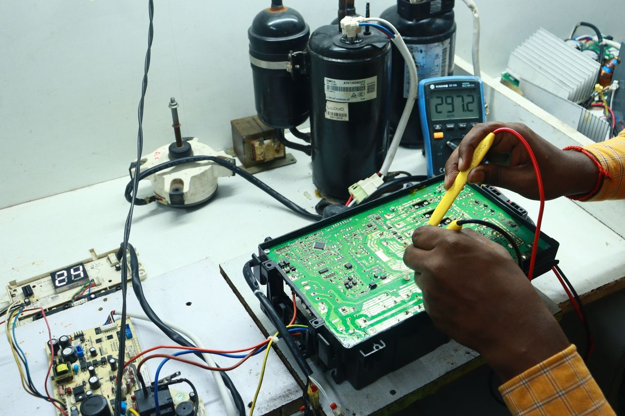 hero-02 Technician working on AC PCB with tools and equipment, captured in New Delhi workshop.
